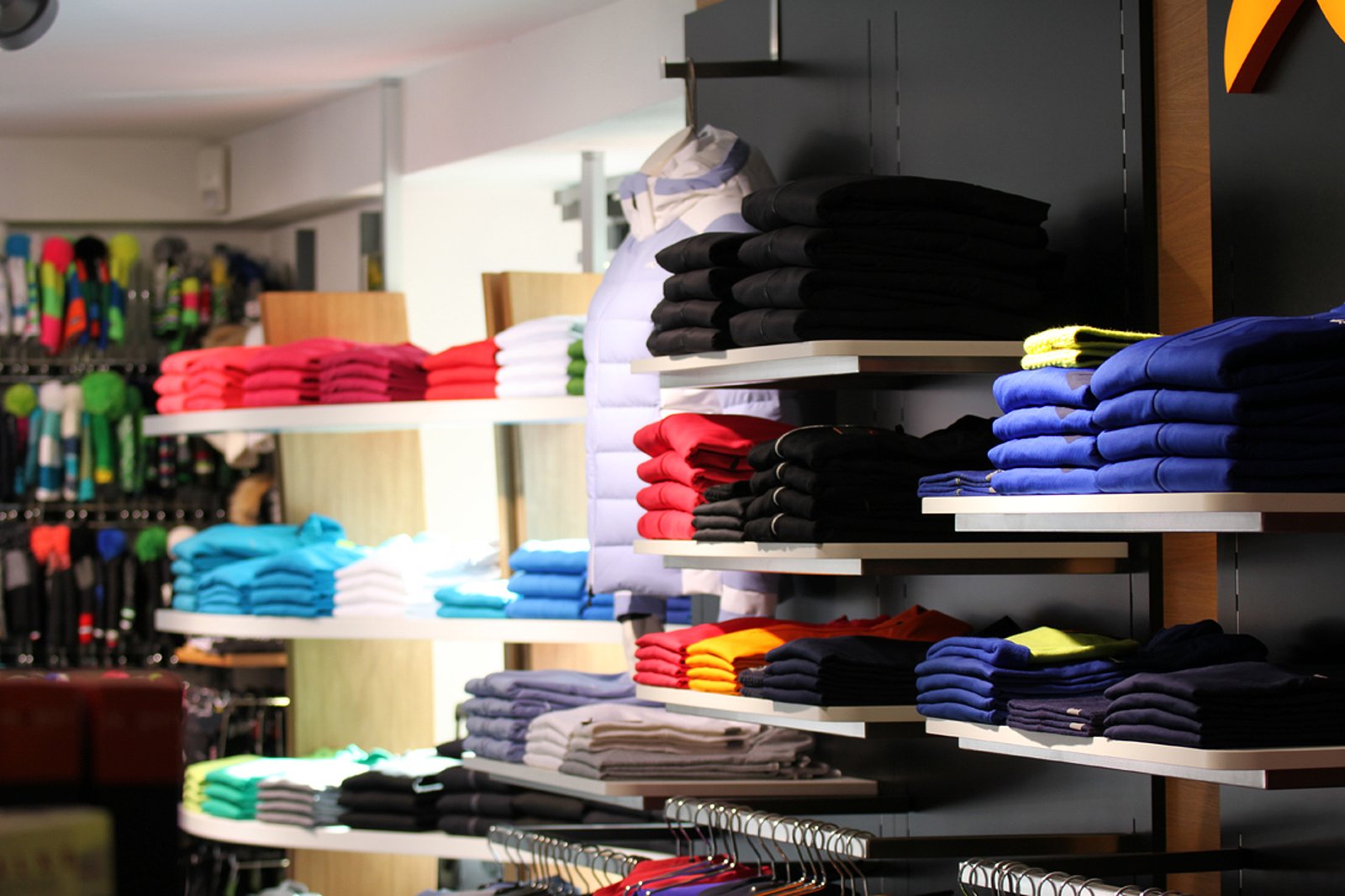 von der Seite fotographiert: Regal voller Stapel von Sportshirts in verschiedenen Farben
